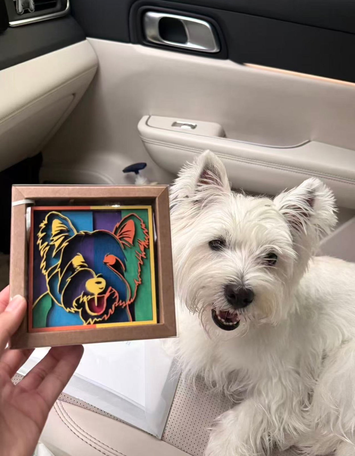 A westie in a car seat beside its carnival color portrait
